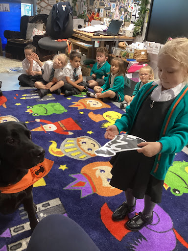 A young girl in academy uniform is pictured interacting with Willow the Dog Mentor in a classroom in the academy building.